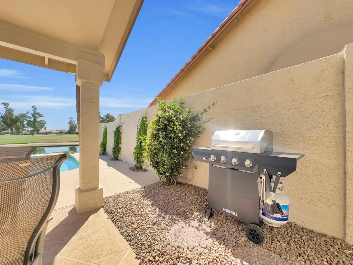 The image features a modern outdoor grill area adjacent to a beautifully landscaped pool, with the grill ready for al fresco barbecues. The pool and landscaped wall create a sense of privacy and leisure, perfectly tailored for outdoor gatherings and poolside dining.