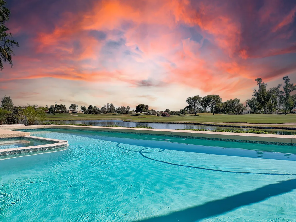 A picturesque sunset scene over the swimming pool, with the water aglow in the evening light and lush greenery framing the view. The tranquil ambience sets the mood for evening gatherings and celebratory meals post-golf.