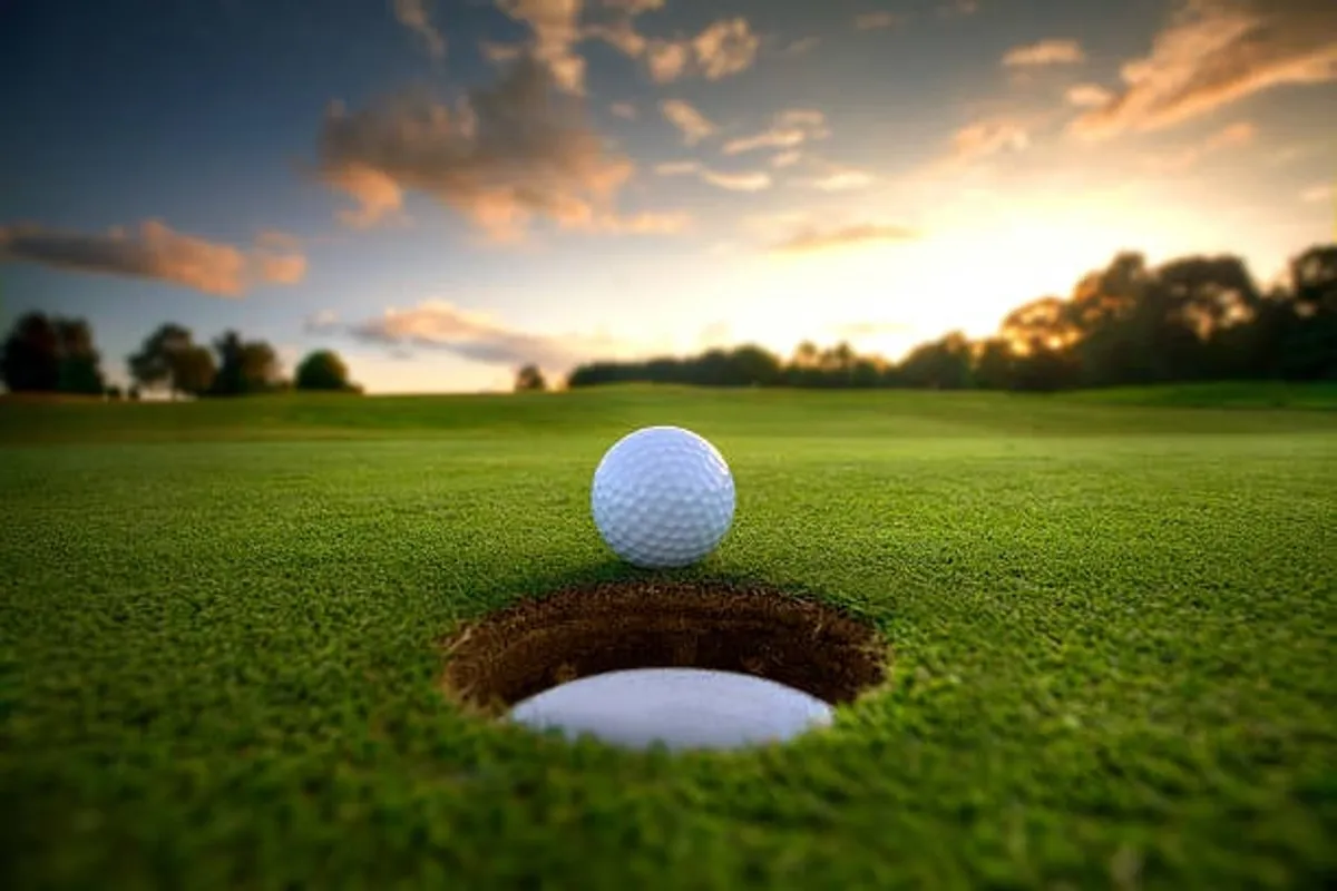 This exterior image spotlights a pristine golf ball resting near a golf hole on vibrant green grass, capturing the essence of the golf experience and the anticipation of a perfect shot. The lush turf and close-up composition evoke excitement and a direct connection to the golf lifestyle.