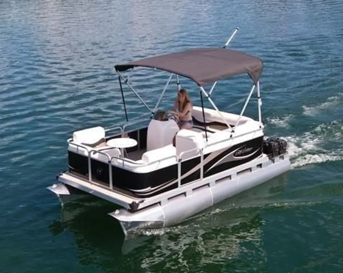 This image captures a pontoon boat on the lake, with a person steering under the canopy. The calm water and leisurely pace epitomize lakeside adventure and recreation, bringing to life the optional pontoon boat rental mentioned in the section.